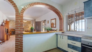 A kitchen with a brick archway, white cabinets, and a wooden countertop. - Cortijo Tom Cortijo Tom Solset (Torrox)