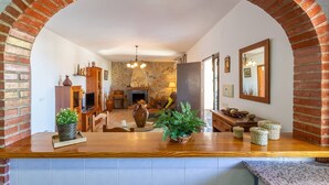A living room with a stone fireplace, wooden furniture, and a brick archway. - Cortijo Tom Cortijo Tom Solset (Torrox)