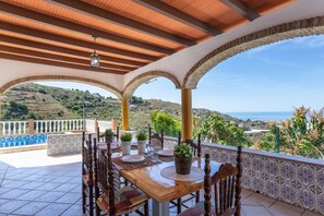 A terrace with a wooden table set for dining, surrounded by arches and a view of the countryside. - Cortijo Tom Cortijo Tom Solset (Torrox)