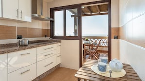 A modern kitchen with white cabinets, a granite countertop, and a view of the sea through a large window. - Villa Margarita Villa Margarita Solset (Velez-Malaga)
