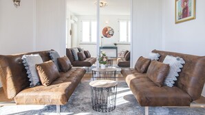 Un salón moderno con dos sofás de cuero marrón, una mesa redonda y un espejo grande que refleja la estancia.