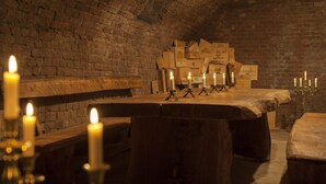 Una habitación tenuemente iluminada con paredes de ladrillo, bancos de madera y velas.