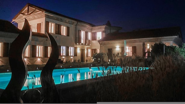 Una casa grande de varios pisos con una piscina al frente.