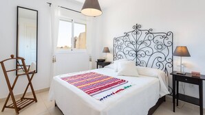 A bedroom with a bed, a bedside table, a lamp, a mirror, and a window. - Duplex Algarrobo Costa Solset (Algarrobo)