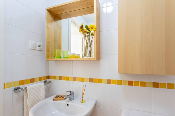 Une salle de bain avec un lavabo blanc, un miroir et un meuble en bois.