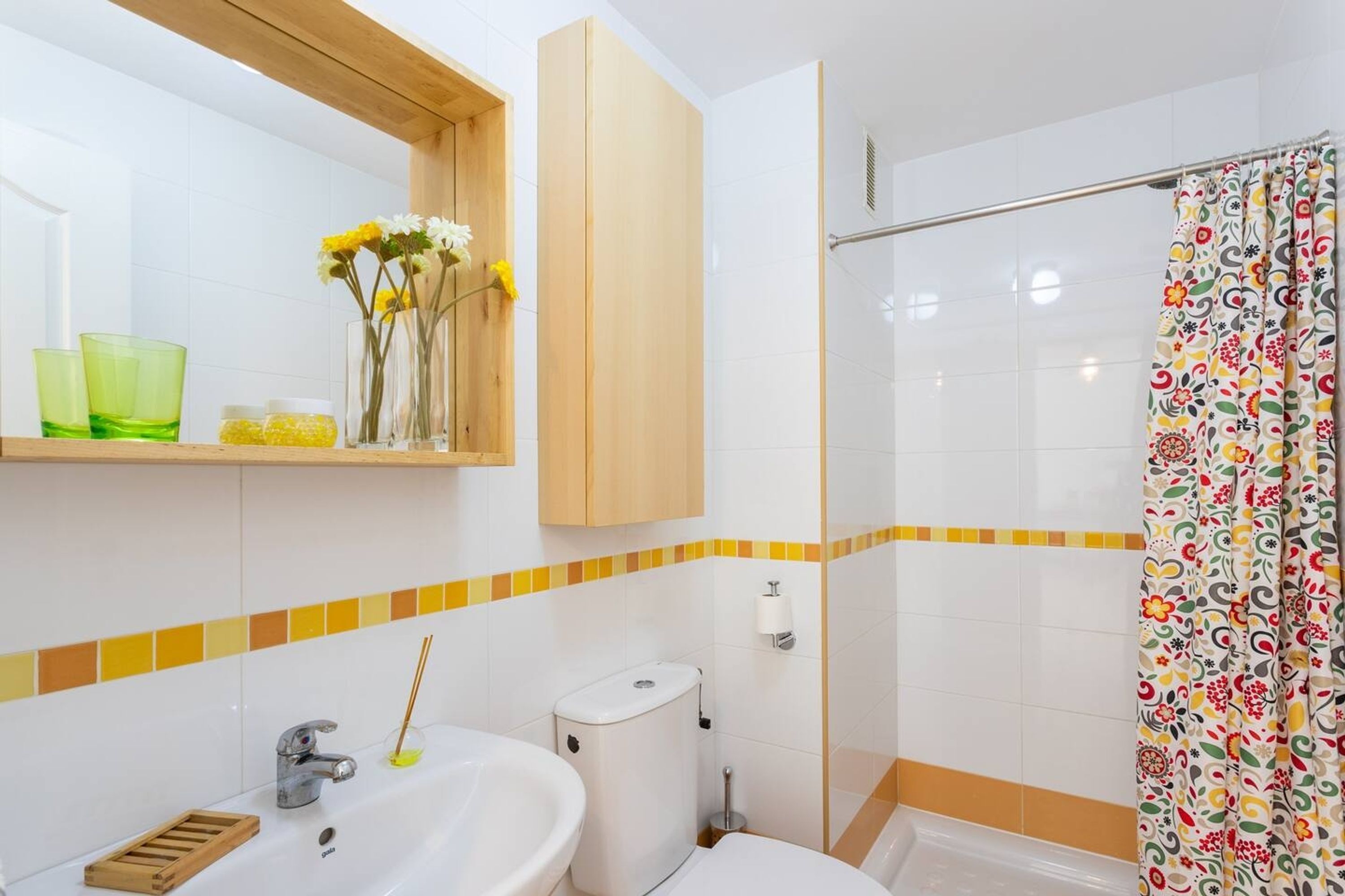 A bathroom with a sink, toilet, shower, and a mirror above the sink.