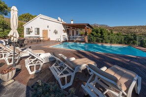 A poolside area with lounge chairs, a table, and a covered seating area.