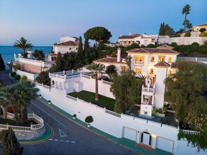 A coastal property with multiple buildings, a swimming pool, and a road with a roundabout.
