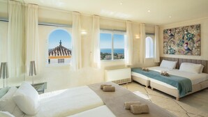 A hotel room with a large bed, a smaller bed, a view of the sea, and a painting on the wall. - Large Luxury Family Villa 500m From Beach (Mijas)