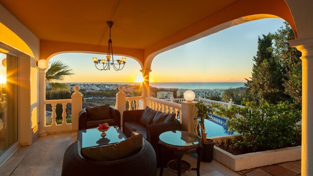 A balcony with a view of the sea, furnished with a sofa, chairs, and a table. - Large Luxury Family Villa 500m From Beach (Mijas)