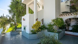 A modern building with a white facade, multiple balconies, and a garden area with various plants. - Large Luxury Family Villa 500m From Beach (Mijas)