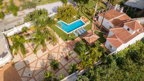 Vue aérienne d’une propriété résidentielle dotée d’une piscine, d’un espace patio et d’une maison avec un toit en tuiles.