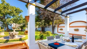 Une terrasse avec une table à manger pour quatre personnes, entourée d’une pergola.