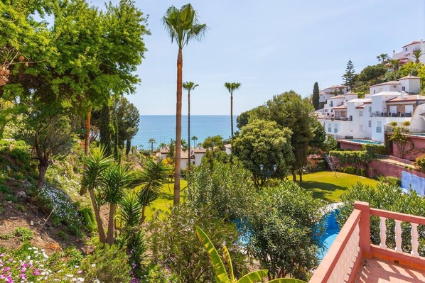 Un quartier résidentiel en bord de mer, avec des maisons blanches, une piscine et une végétation luxuriante.