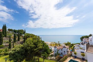 Un quartier résidentiel situé sur la côte, avec des bâtiments blancs, un ciel d’un bleu limpide et une vue sur la mer.