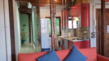 A modern interior with a red sofa, blue cushions, a wooden staircase, and a glass partition.