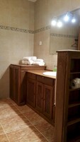 Un baño con tocador de madera, inodoro y lavamanos.