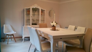 Comedor con una mesa blanca, sillas, un armario y un espejo.