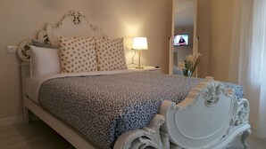 A neatly made bed with a patterned bedspread, a white headboard with ornate carvings, and a bedside lamp. - Apartamento Deluxe 2 Cason DEL Corpus 2 Go Native Toledo 11 Plazas (Toledo)