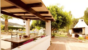 An outdoor patio with a wooden table and chairs, a barbecue grill, and a pool in the background. - Villa La Siesta in Javea (Javea)