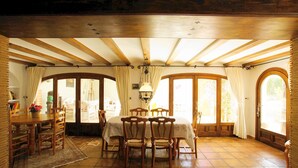 A dining area with a wooden table and chairs, large windows, and a tiled floor. - Villa La Siesta in Javea (Javea)