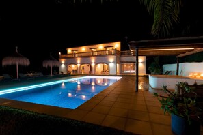 A nighttime view of a hotel with a swimming pool, outdoor seating, and a well-lit facade. - Villa Paulina in Javea (Javea)