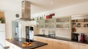 Una cocina moderna con una isla central, electrodomésticos integrados y varios armarios de almacenaje.