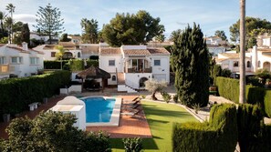 Een villa met zwembad, overdekt terras en een verzorgde tuin.