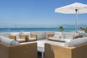 A rooftop terrace with wicker furniture, a white umbrella, and a view of the sea and mountains. - Villa Frontline Beach Costabella - Marbella (Marbella)