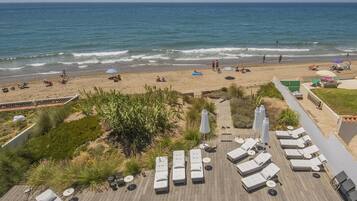 A beachside resort with sun loungers, a pool, and a view of the ocean.