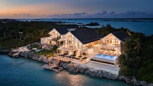 A large, modern beachfront property with multiple bedrooms, a swimming pool, and a dock.