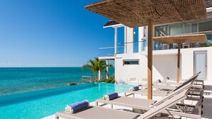 A poolside area with lounge chairs and a view of the ocean.