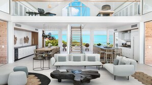 A spacious, modern living area with a large sofa, a coffee table, and a view of the sea.