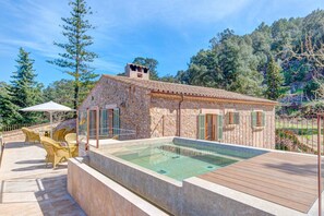 A stone building with a swimming pool, outdoor seating, and a mountainous backdrop. - Finca Val de Marc in Pollen a (Pollença)