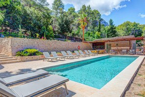 A rectangular swimming pool with lounge chairs and a small building with a tiled roof. - Finca Val de Marc in Pollen a (Pollença)