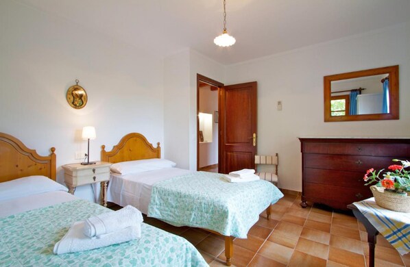 Una habitación de hotel con dos camas, un aparador de madera, un espejo y suelo de baldosas.