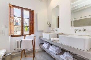A bathroom with two sinks, a large mirror, a window with wooden frames, and a radiator. - Casa Campomar by Vida Villas (Pollença)