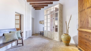 A room with a wooden bench, a large cabinet, and a vase with branches. - Casa Campomar by Vida Villas (Pollença)