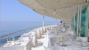Un restaurant en bord de mer, avec des tables nappées de blanc et une vue sur l’océan.