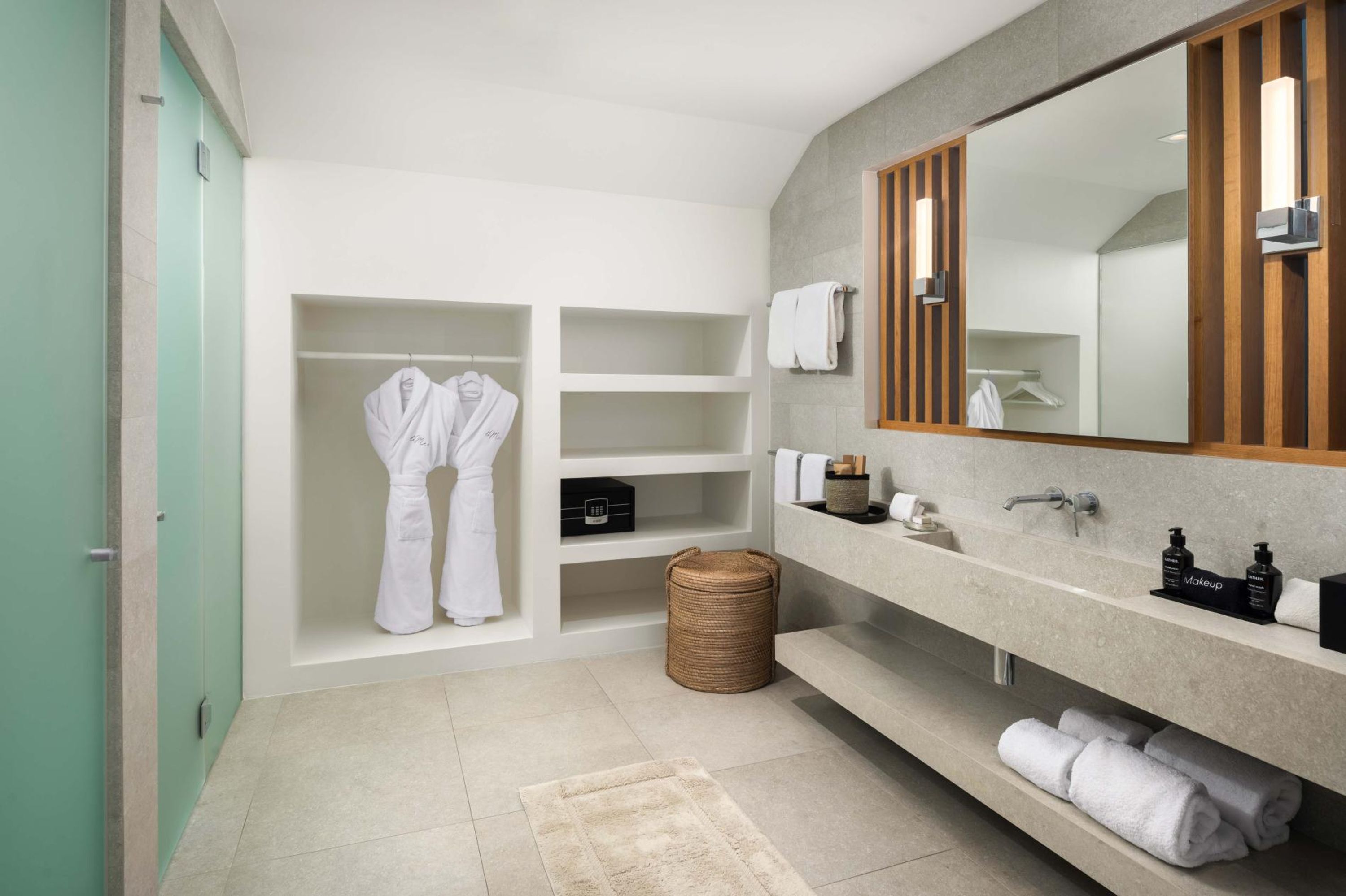 Un baño moderno con un espejo grande, estantes empotrados, un tocador con lavamanos y una cesta de mimbre.