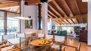 A spacious living area with a glass dining table, wooden chairs, a sofa, and a bookshelf. - El Vilar 60 Villa Puerto Pollenca (Pollença)