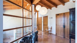 A spacious room with wooden beams, large windows, and a chandelier. - El Vilar 60 Villa Puerto Pollenca (Pollença)