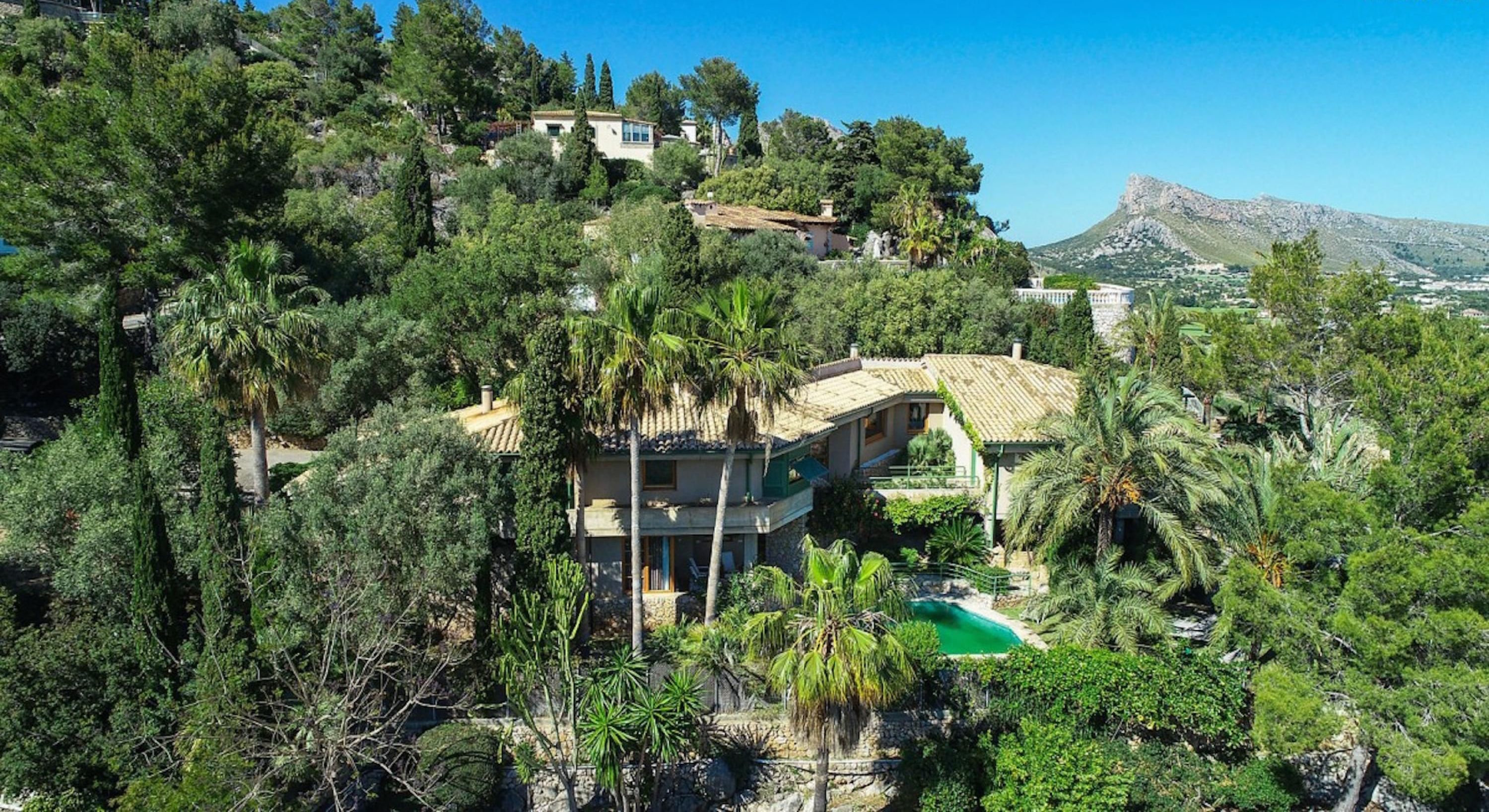 A villa surrounded by lush greenery and a mountain backdrop.