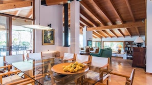 A spacious living area with a glass dining table, wooden chairs, a sofa, and a bookshelf. - El Vilar 60 Villa Puerto Pollenca (Pollença)