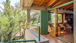 A modern outdoor balcony with a concrete floor, green railing, and a view of lush greenery. - El Vilar 60 Villa Puerto Pollenca (Pollença)