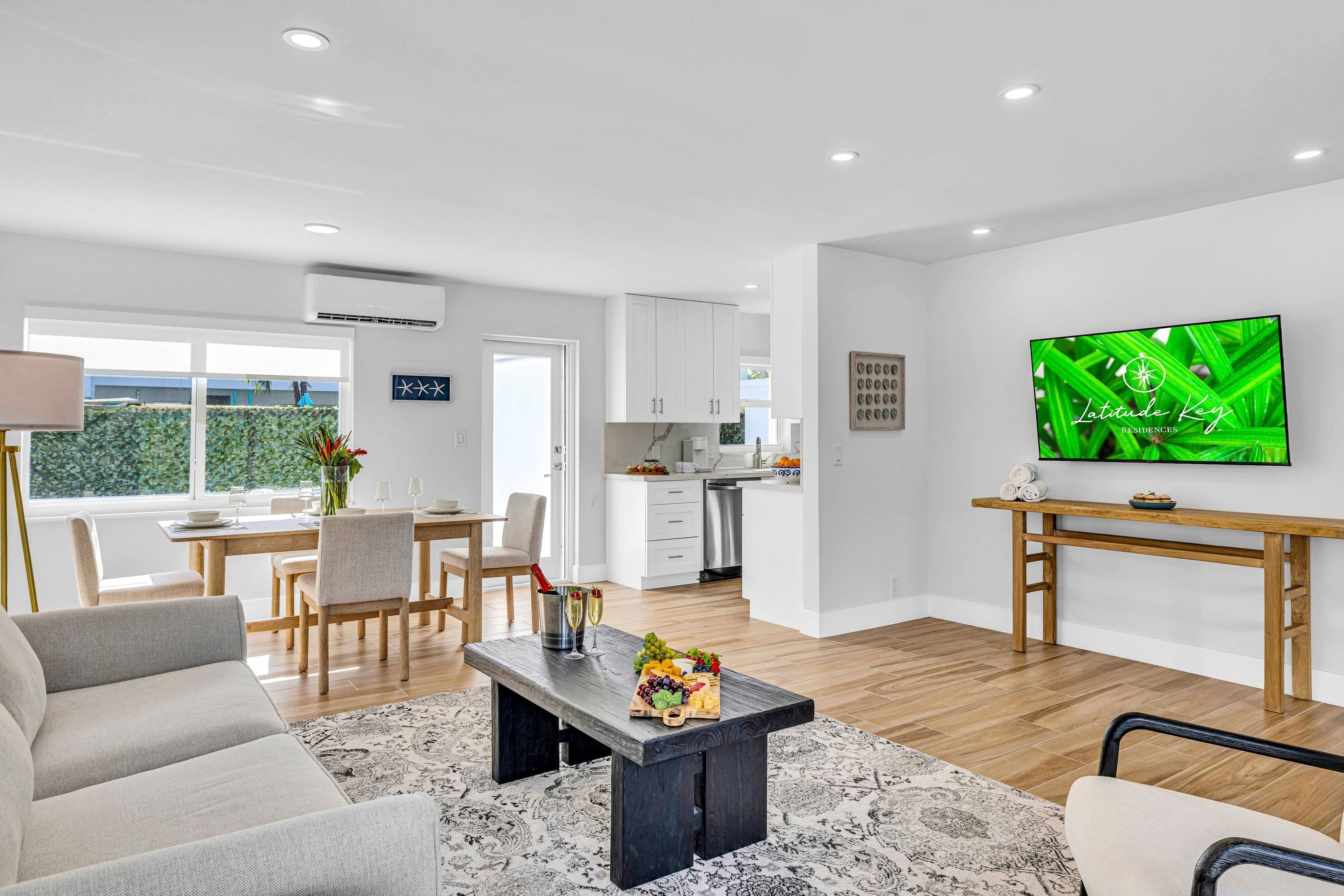 Una sala de estar moderna con comedor, cocina y un televisor que muestra 'Latitude Key Residences'.