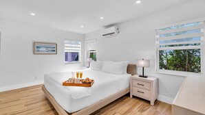 Une chambre moderne avec un grand lit, une table de chevet et une fenêtre équipée de stores.