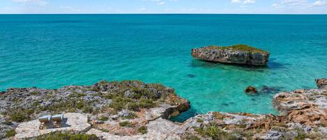 A rocky coastal area with clear turquoise water and a small island.