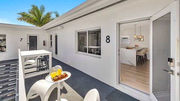 A modern, clean room with a dining area, a kitchen, and a door marked with the number 8. - Beach Condo King Bed Lush Patio w BBQ Birch Key Eight (Fort Lauderdale)