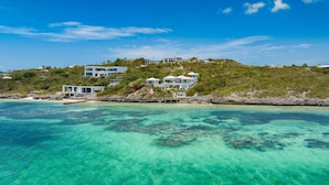 A coastal property with multiple modern villas, a rocky shoreline, and clear turquoise waters. - Villa Eden in Providenciales (Providenciales)